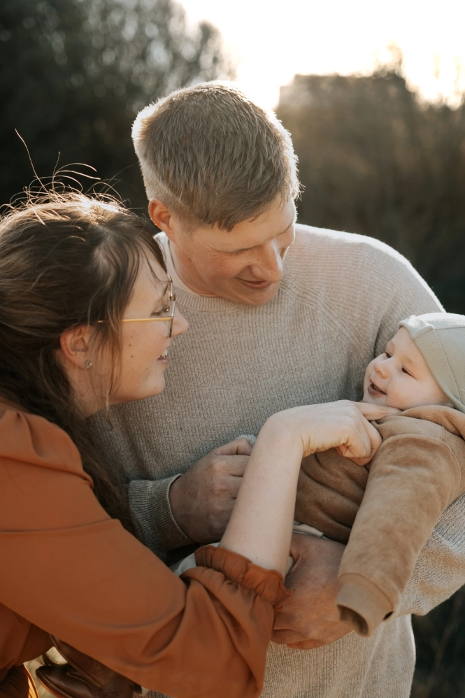 Foto van een man en vrouw samen met hun kindje in een veld.